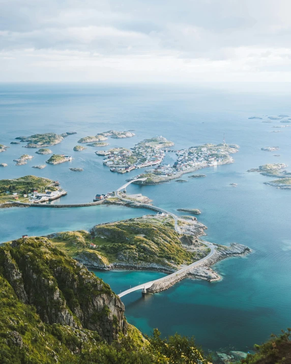 a large body of water sitting on top of a lush green hillside, by Roar Kjernstad, pexels contest winner, fishing town, many islands, flatlay, shades of blue and grey