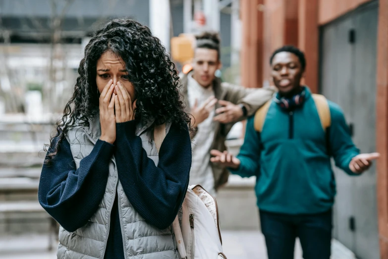 a woman covers her face in front of a group of people, flowing mucus, in an urban setting, background image, schools
