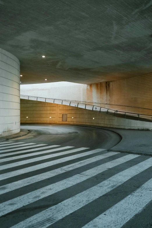 a man riding a skateboard up the side of a ramp, inspired by Tadao Ando, unsplash, conceptual art, set inside of parking garage, crosswalk, rounded architecture, nadav kander