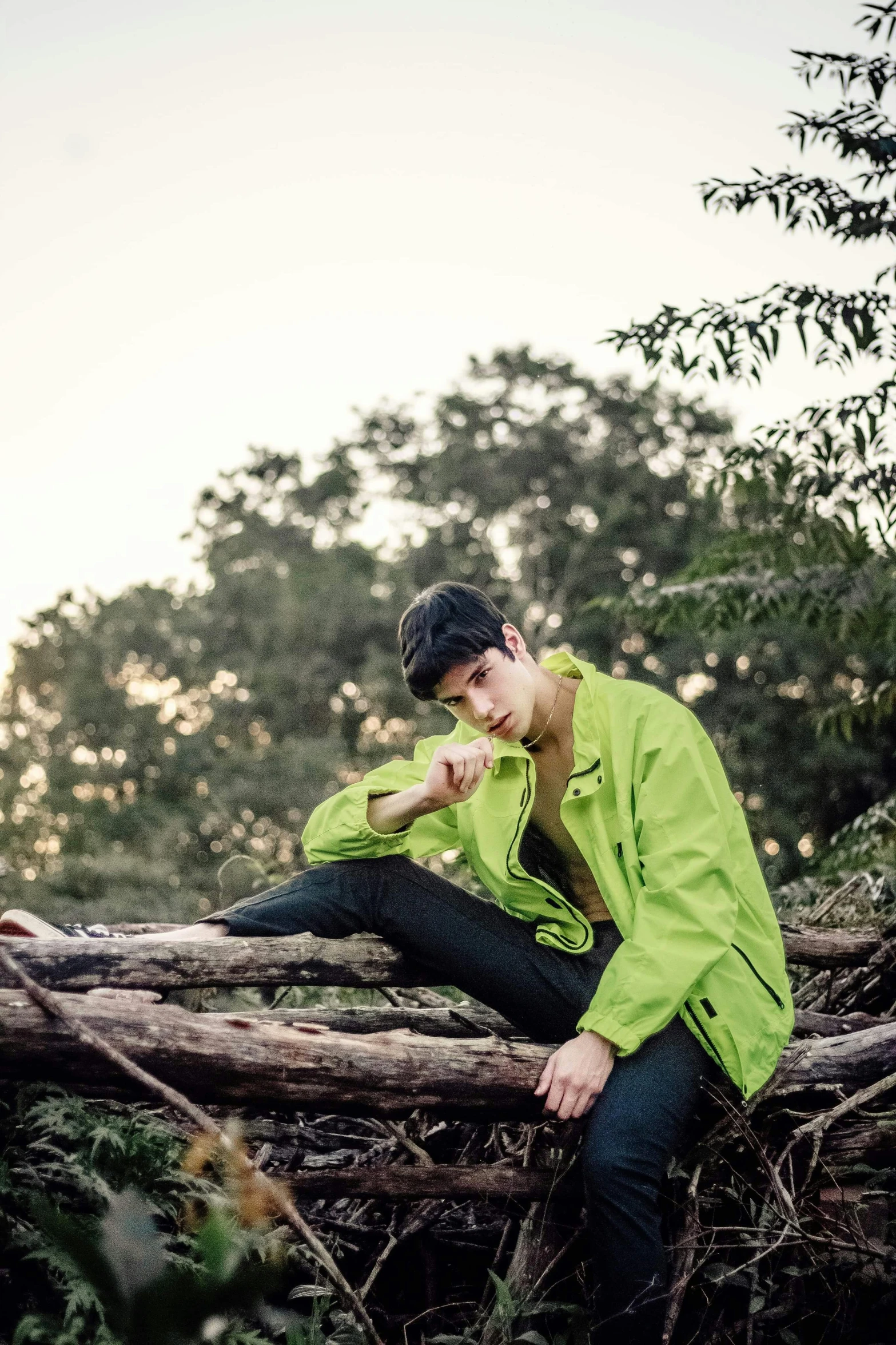 a man sitting on top of a fallen tree, a portrait, unsplash, lime green, declan mckenna, profile image, shot with a camera flash