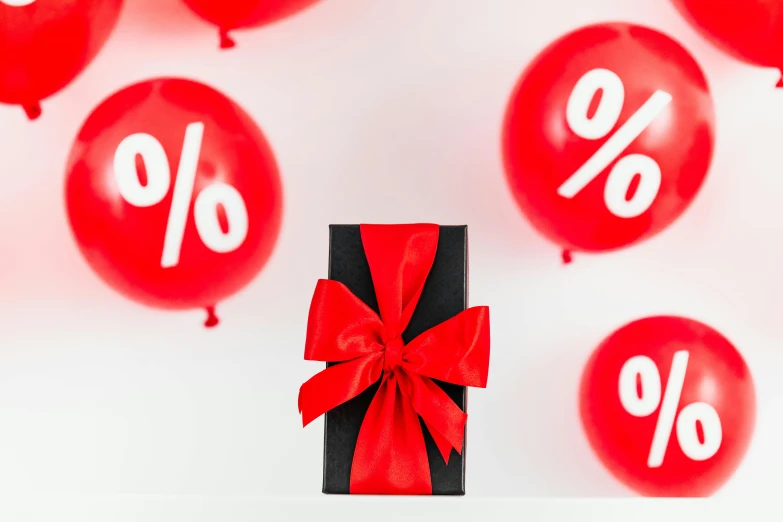 a black gift box tied with a red ribbon surrounded by red balloons, a cartoon, by Julia Pishtar, trending on unsplash, letterism, ornamental bow, sales, proportions off, product display photograph