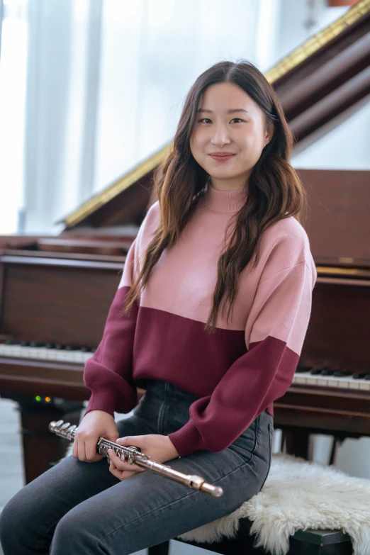 a woman sitting on a stool in front of a piano, inspired by Song Xu, happening, wearing casual sweater, maroon, pink, medium close-up shot