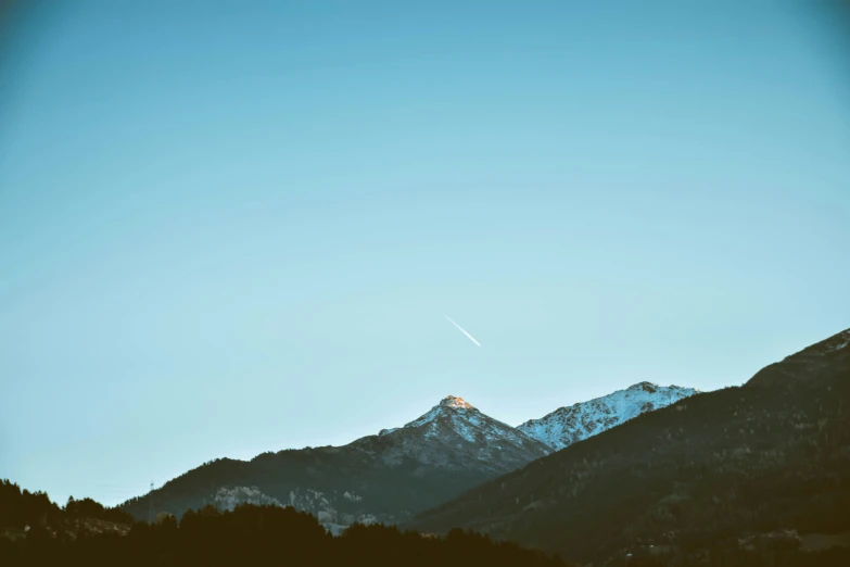 a plane is flying over a mountain range, by Niko Henrichon, unsplash contest winner, minimalism, clear blue sky vintage style, early evening, whistler, sword pointed at sky