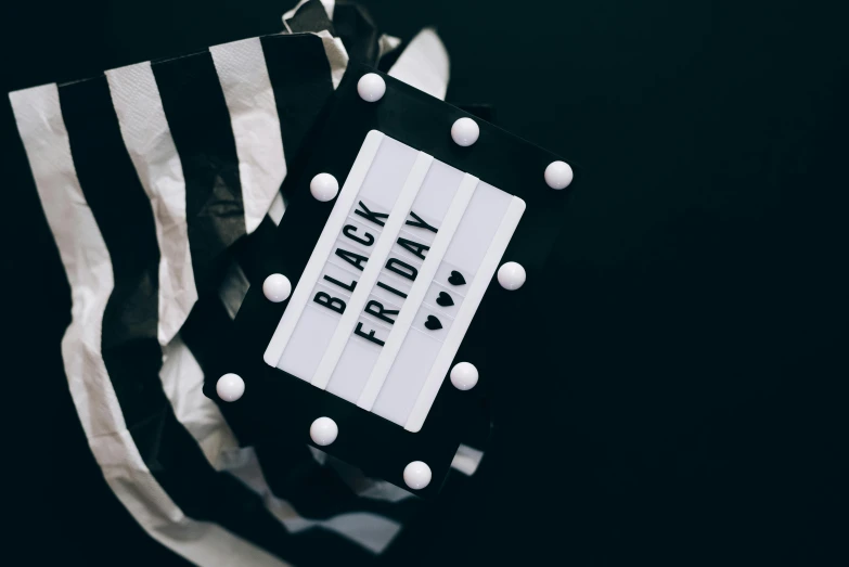 a black and white bag sitting on top of a table, by Julia Pishtar, pexels contest winner, bright signage, costume, black vertical slatted timber, gifts