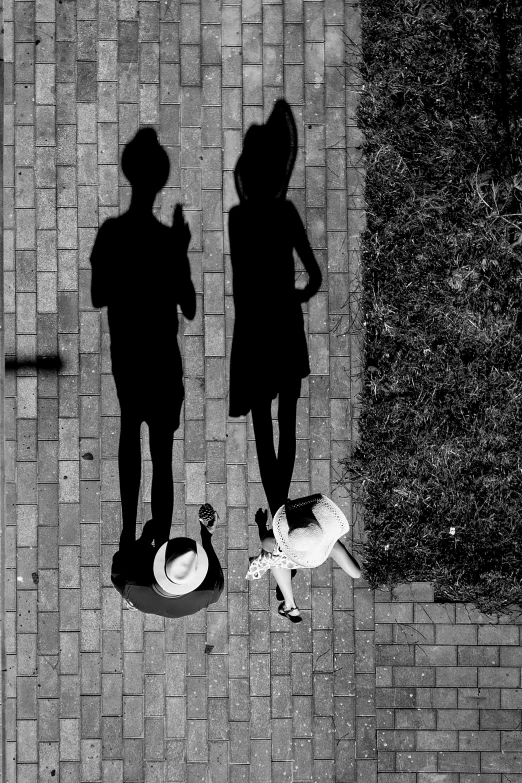 a black and white photo of two people and a dog, unsplash contest winner, conceptual art, long shadow, flat lay, sisters, drone photograpghy