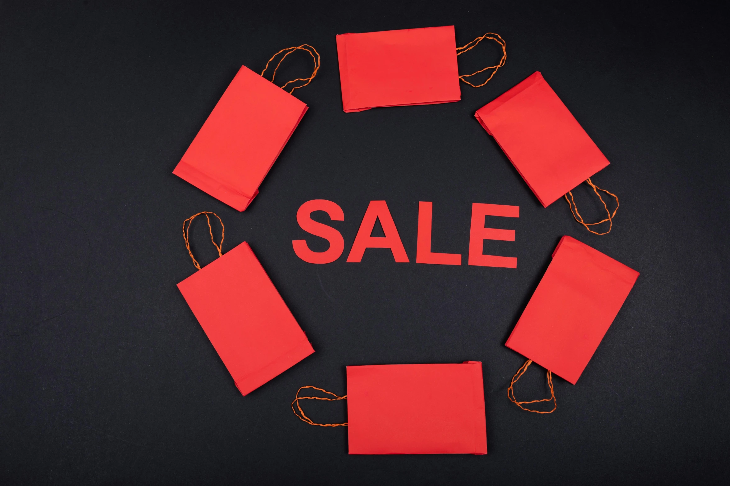 a sale sign surrounded by shopping bags on a black background, a photo, by Julia Pishtar, pexels contest winner, bauhaus, dressed in red paper bags, square, circle, symmetrical