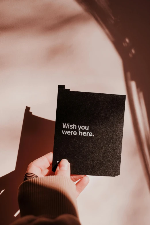 a person holding a card that says wish you were here, by Julia Pishtar, happening, vantablack, vsco, greeting card, multiple stories