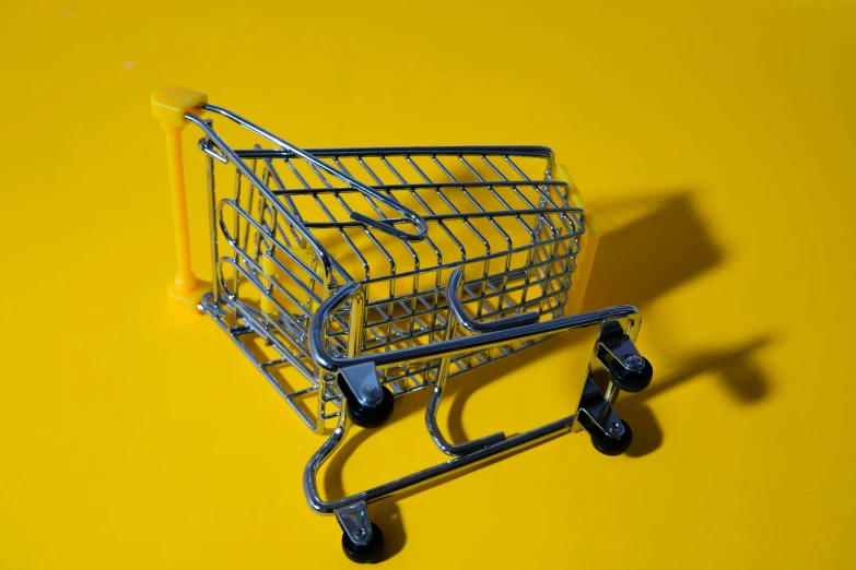a shopping cart sitting on top of a yellow surface