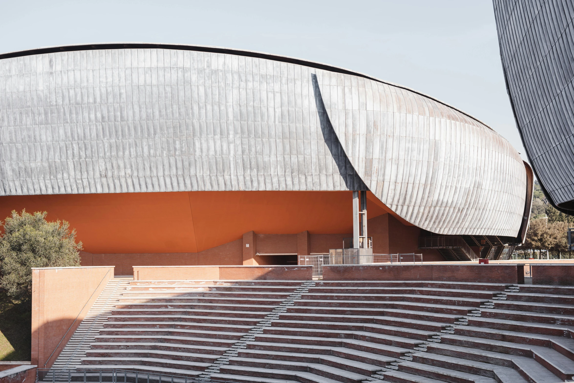 a man riding a skateboard up the side of a ramp, by Carlo Martini, unsplash contest winner, modernism, terracotta, photo of a huge theaterstage, rounded roof, standing in a stadium