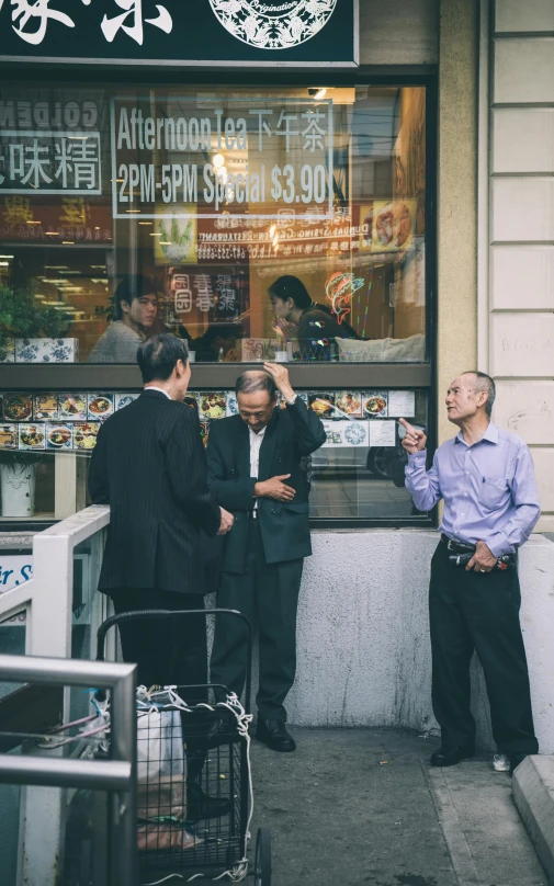 a group of men standing in front of a store, a photo, by Matt Stewart, pexels contest winner, gta chinatown, eating outside, wearing a worn out suit, three quarter profile