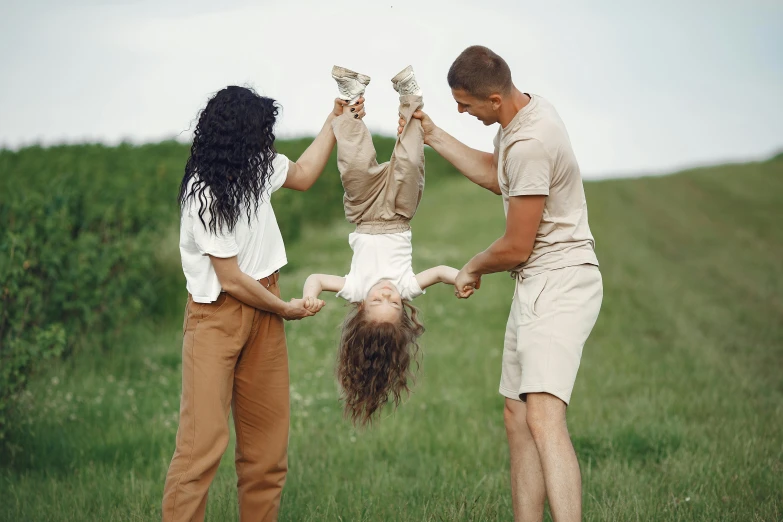 a man holding a little girl upside down in a field, inspired by The Family Circus, pexels contest winner, renaissance, khakis, portrait of family of three, flying hair, slightly smooth