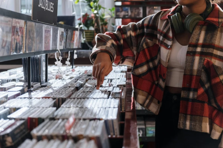 a woman standing in front of a display of cds, trending on pexels, walton's five and dime, digging, lofi hip hop, bottom angle