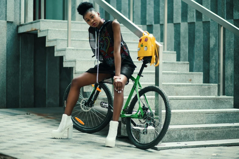 a woman sitting on top of a bike next to stairs, pexels contest winner, afrofuturism, green and yellow, with a backpack, handsome girl, ( ( dark skin ) )