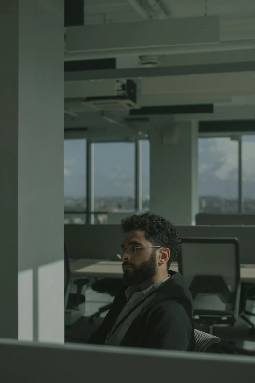 a man sitting at a desk in an office, by Attila Meszlenyi, pexels contest winner, an arab standing watching over, hq 8k cinematic, view from the side, still frame from a movie