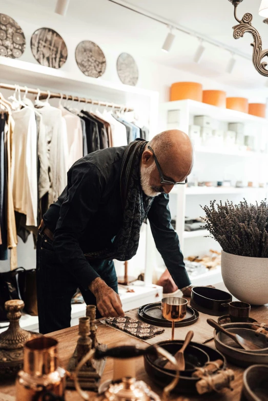 a man that is standing in front of a table, a silk screen, styling, black and terracotta, the store, plating