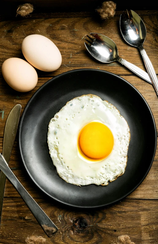 an egg in a frying pan on a wooden table, by Matthias Stom, shutterstock, instagram post, various posed, small, on a plate