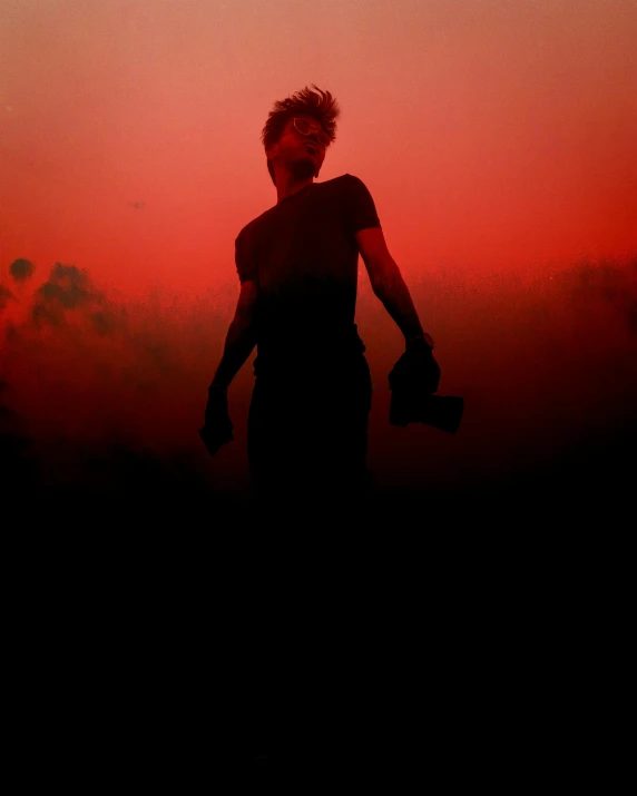 a person standing in the middle of a field at sunset, an album cover, pexels contest winner, gradient red to black, tear gas, dust clouds | homoerotic, red on black