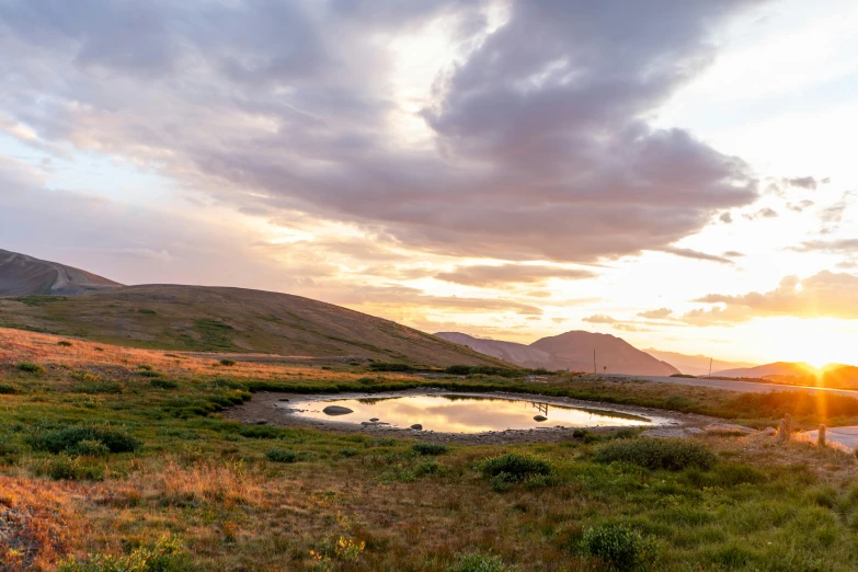 a body of water sitting in the middle of a field, by Hallsteinn Sigurðsson, unsplash contest winner, land art, sunset in a valley, pond, 2 0 0 0's photo, conde nast traveler photo