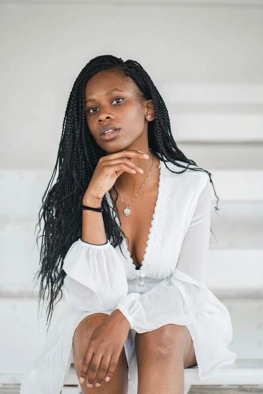 a woman in a white dress sitting on some steps, by Dulah Marie Evans, long black braided hair, on a white table, looking confident, riyahd cassiem