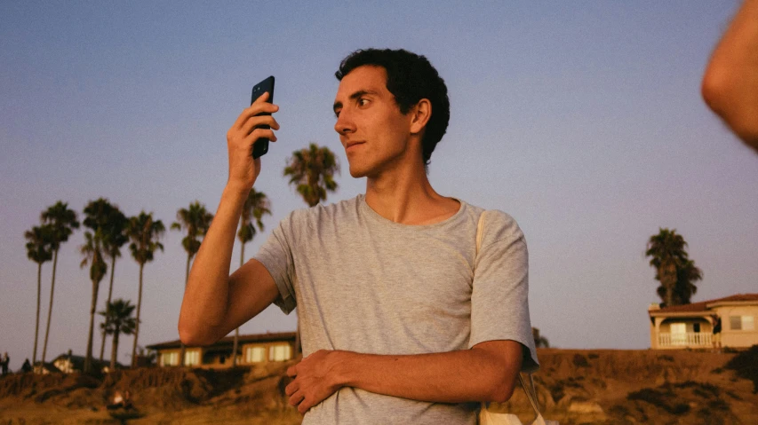 a man holding a cell phone up to his ear, pexels contest winner, serial art, standing near the beach, clear julian lage face, perfectly lit. movie still, h3h3