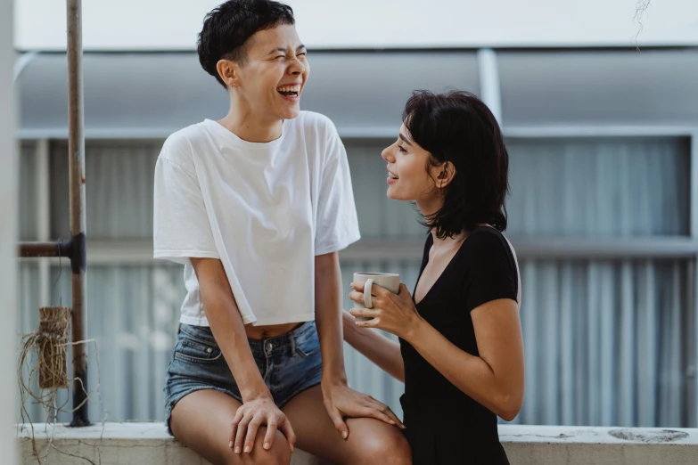 a man and a woman sitting next to each other, trending on pexels, happening, lesbian, earing a shirt laughing, balcony, asian women
