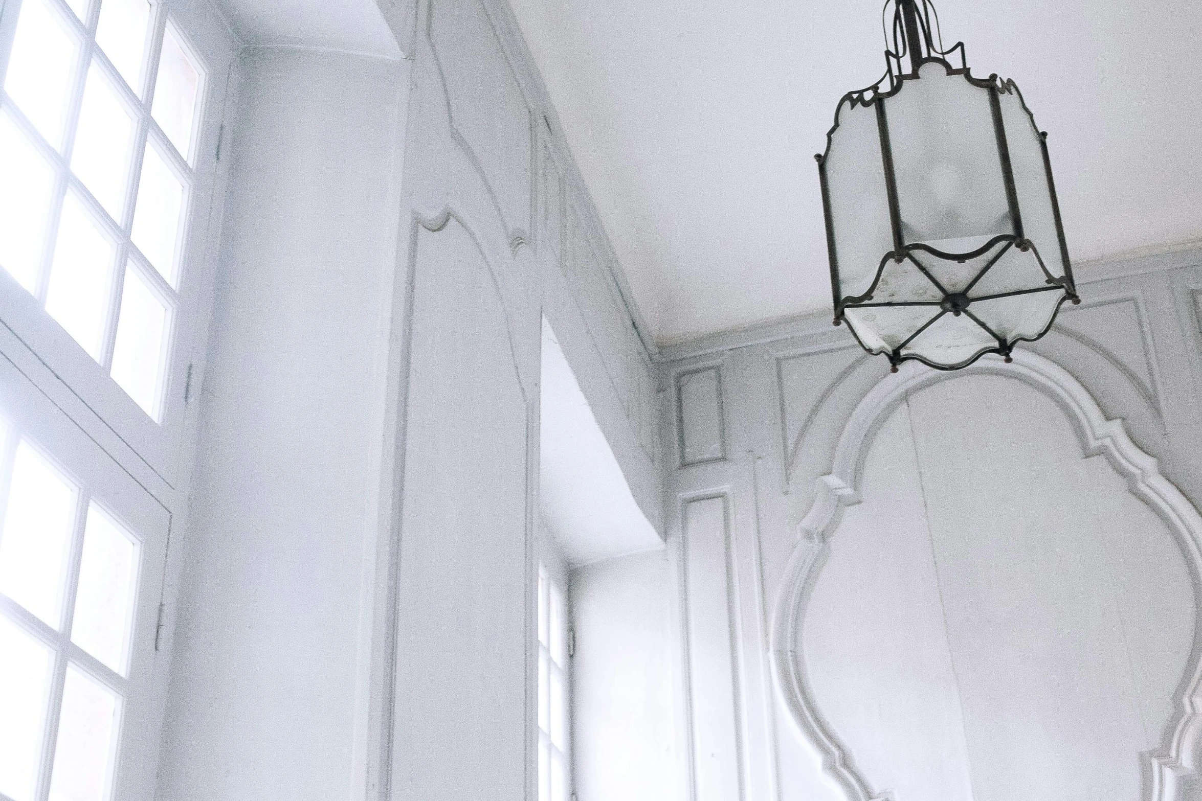 a lamp hanging from the ceiling in a room, an ambient occlusion render, inspired by Jean Tabaud, unsplash, smooth panelling, whitewashed buildings, lanterns, looking around a corner