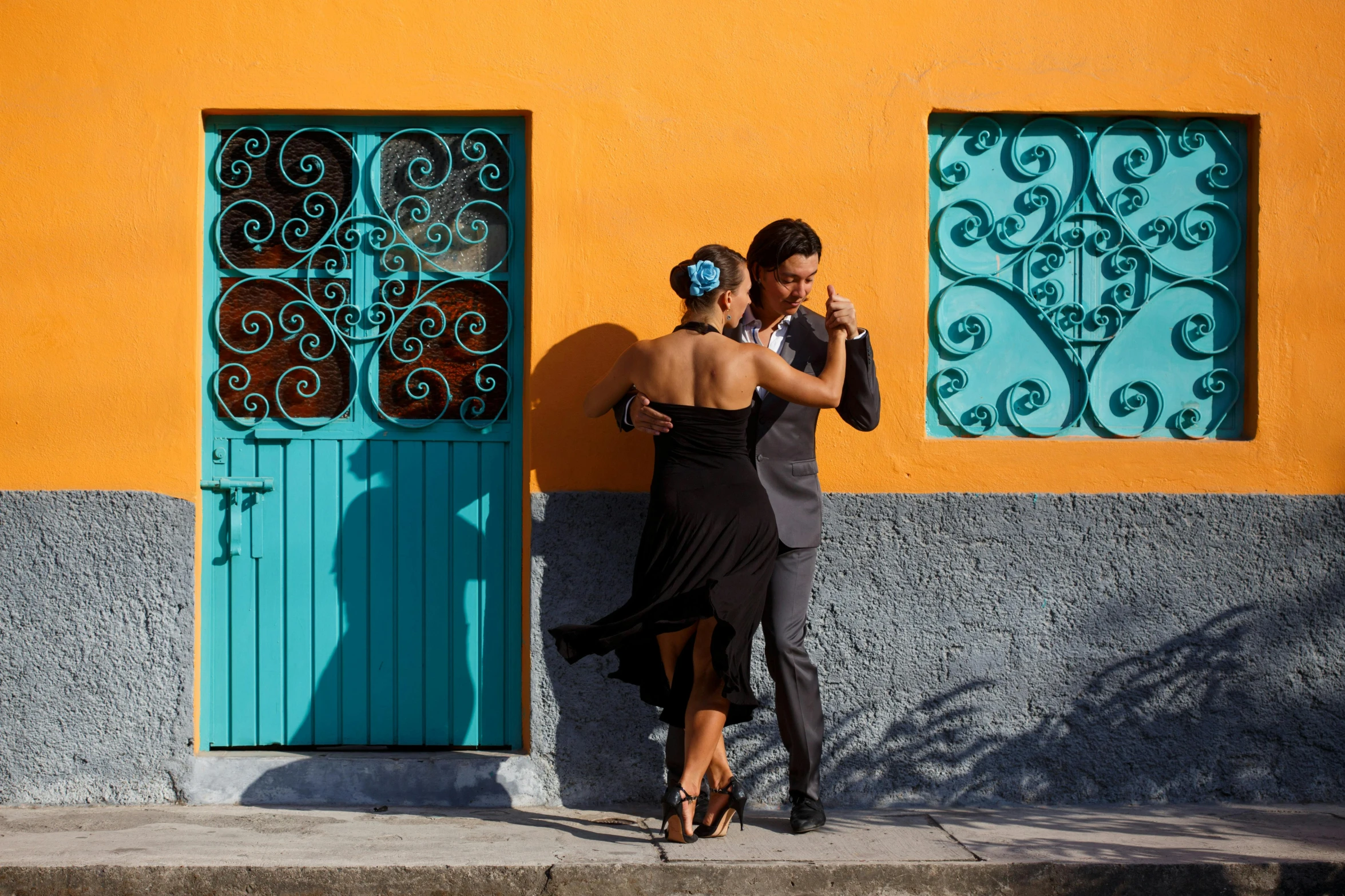 a couple of people that are standing in front of a building, pexels contest winner, arabesque, salsa social dance, cyan and orange, square, chilean