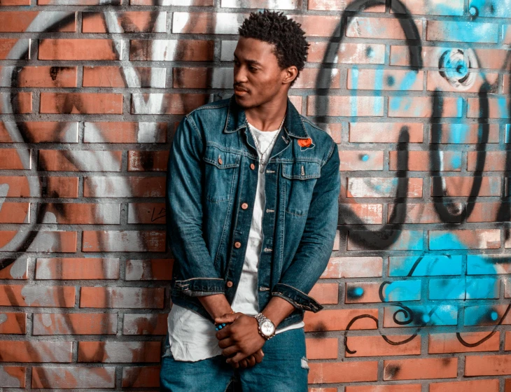 a man standing in front of a graffiti covered wall, an album cover, pexels contest winner, wearing a jeans jackets, mkbhd, profile image, concert photo