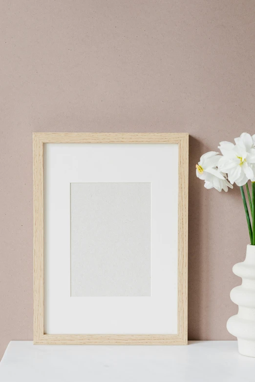 a vase filled with white flowers next to a picture frame, poster art, pexels contest winner, postminimalism, beige color scheme, orchid, product introduction photo, square pictureframes