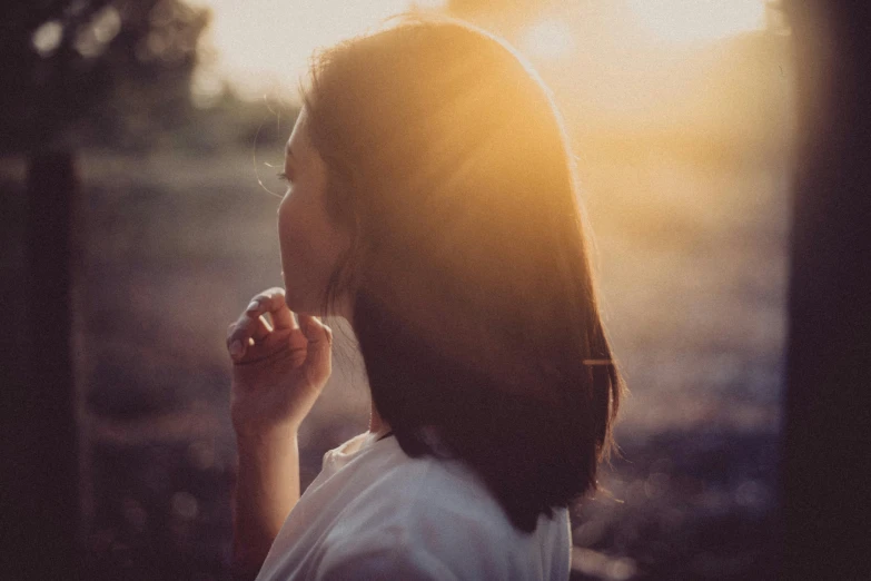 a woman in a white shirt eating a donut, pexels contest winner, romanticism, in a sunset haze, paul barson, looking off into the sunset, an asian woman