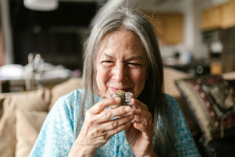 a woman sitting on a couch eating a piece of food, pexels contest winner, hurufiyya, with an ashtray on top, she is about 7 0 years old, avatar image, marijuana