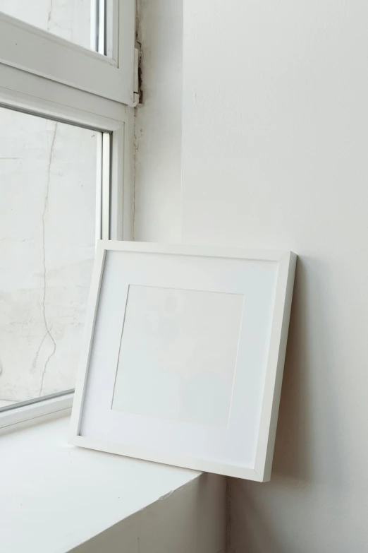 a picture frame sitting on top of a window sill, a minimalist painting, promo image, all white, square face, tightly framed