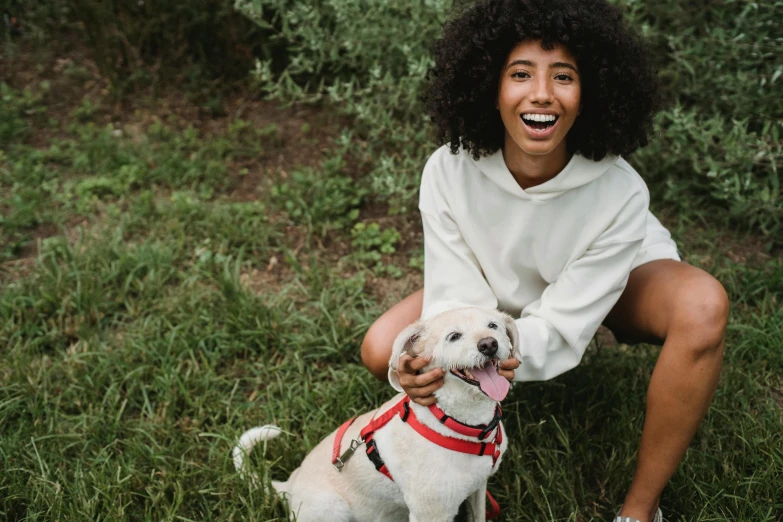 a woman kneeling in the grass with a dog, pexels contest winner, mixed-race woman, smiling with confidence, avatar image, white