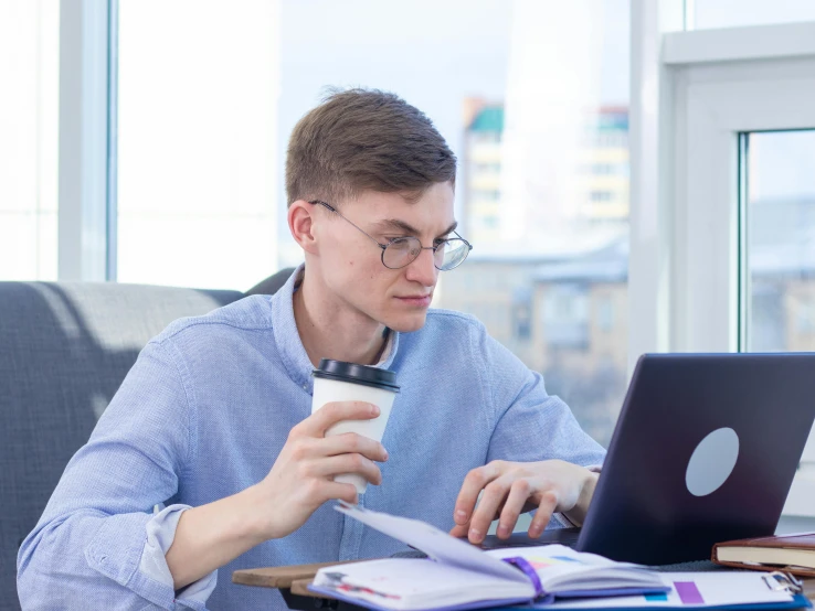 a man sitting at a table with a laptop and a cup of coffee, school curriculum expert, profile image, non-binary, commercial