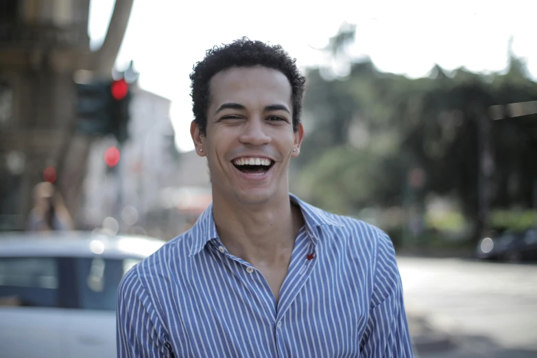 a man smiles while standing on a city street, by Nadir Afonso, light skin tone, maxwell boas, portait image