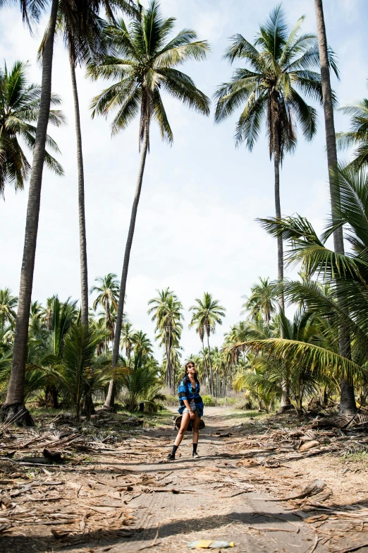 a man running down a dirt road surrounded by palm trees, imaan hammam, wearing adventuring gear, panoramic view of girl, posed