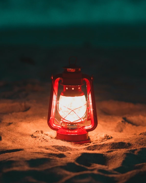 a red lantern sitting on top of a sandy beach, lit up in a dark room, detailed product image, multiple stories, bright red