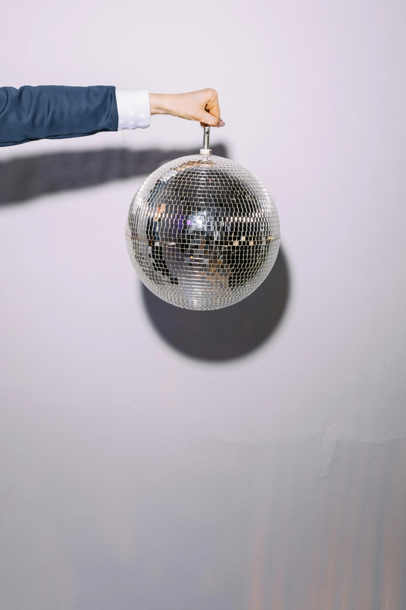a man in a suit holding a disco ball, an album cover, by Gavin Hamilton, trending on unsplash, light and space, silver，ivory, 15081959 21121991 01012000 4k, hanging, photographed for reuters