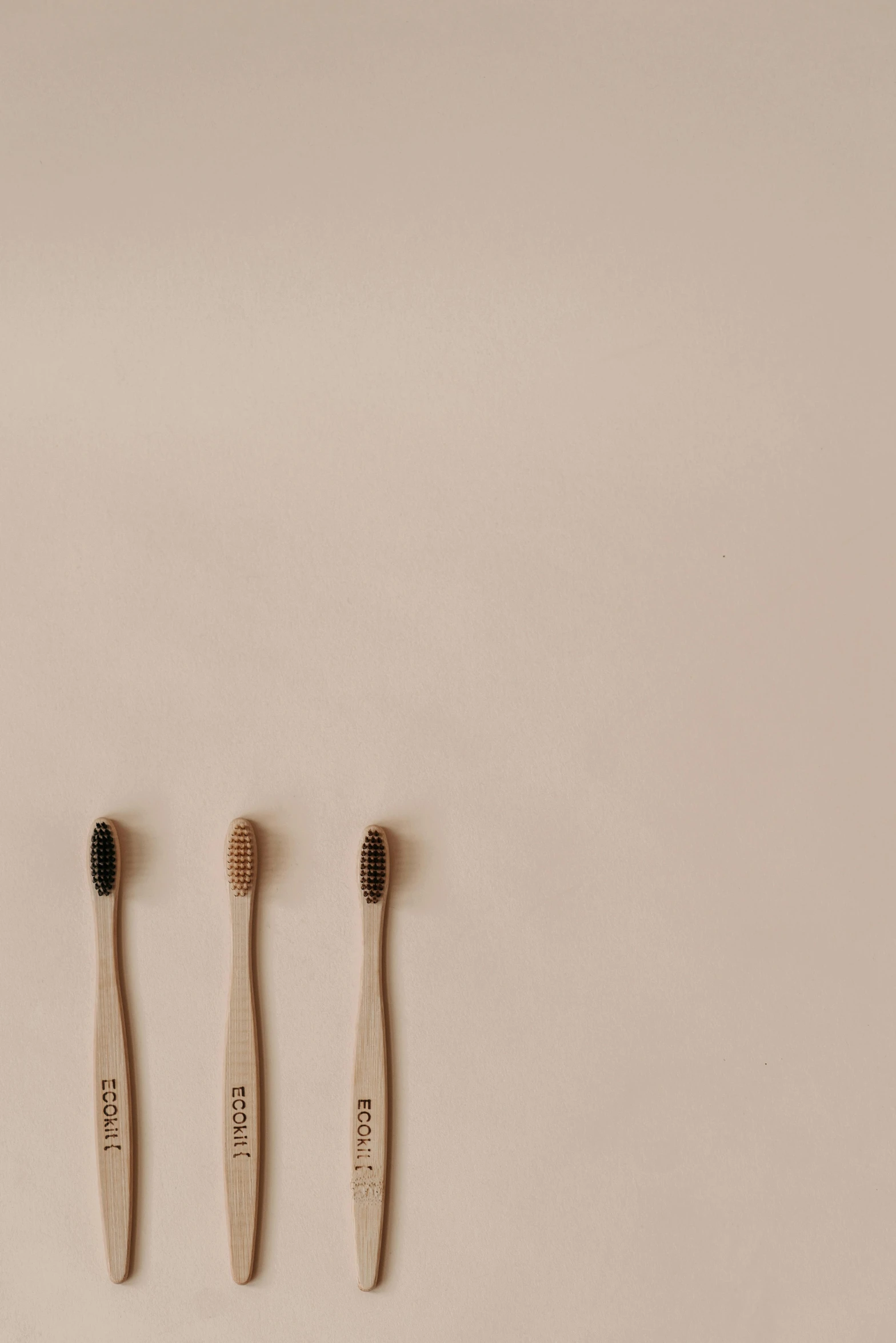 three toothbrushes sitting next to each other on a white surface, a picture, by Andries Stock, unsplash, minimalism, beige mist, made of wood, people, carbon