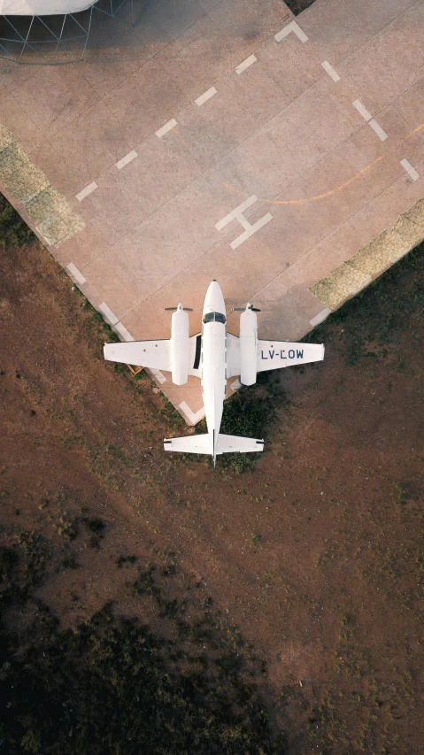 a small white airplane sitting on top of a runway, by Daniel Taylor, unsplash contest winner, conceptual art, high angle view, space ship cemetery outer space, strafing attack plane, instagram post