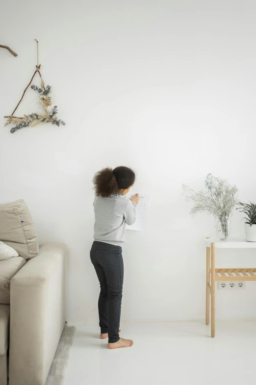 a woman standing in a living room next to a couch, kid drawing, white background wall, 2019 trending photo, decorations