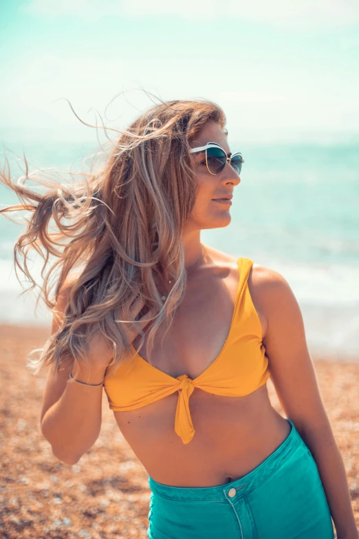 a woman standing on top of a beach next to the ocean, wavy hair yellow theme, implanted sunglasses, close up of a blonde woman, avatar image