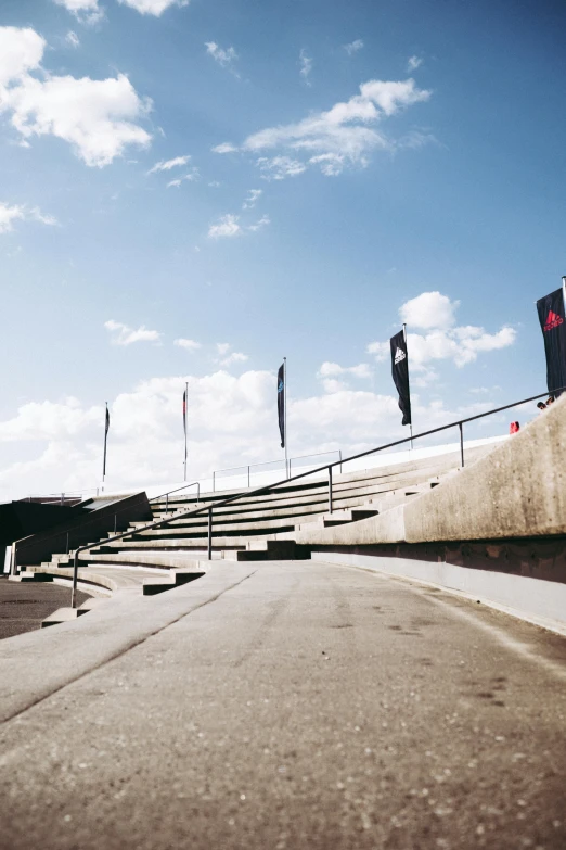 a man flying through the air while riding a skateboard, unsplash, brutalism, at circuit de spa francorchamps, flags, steps leading down, panoramic