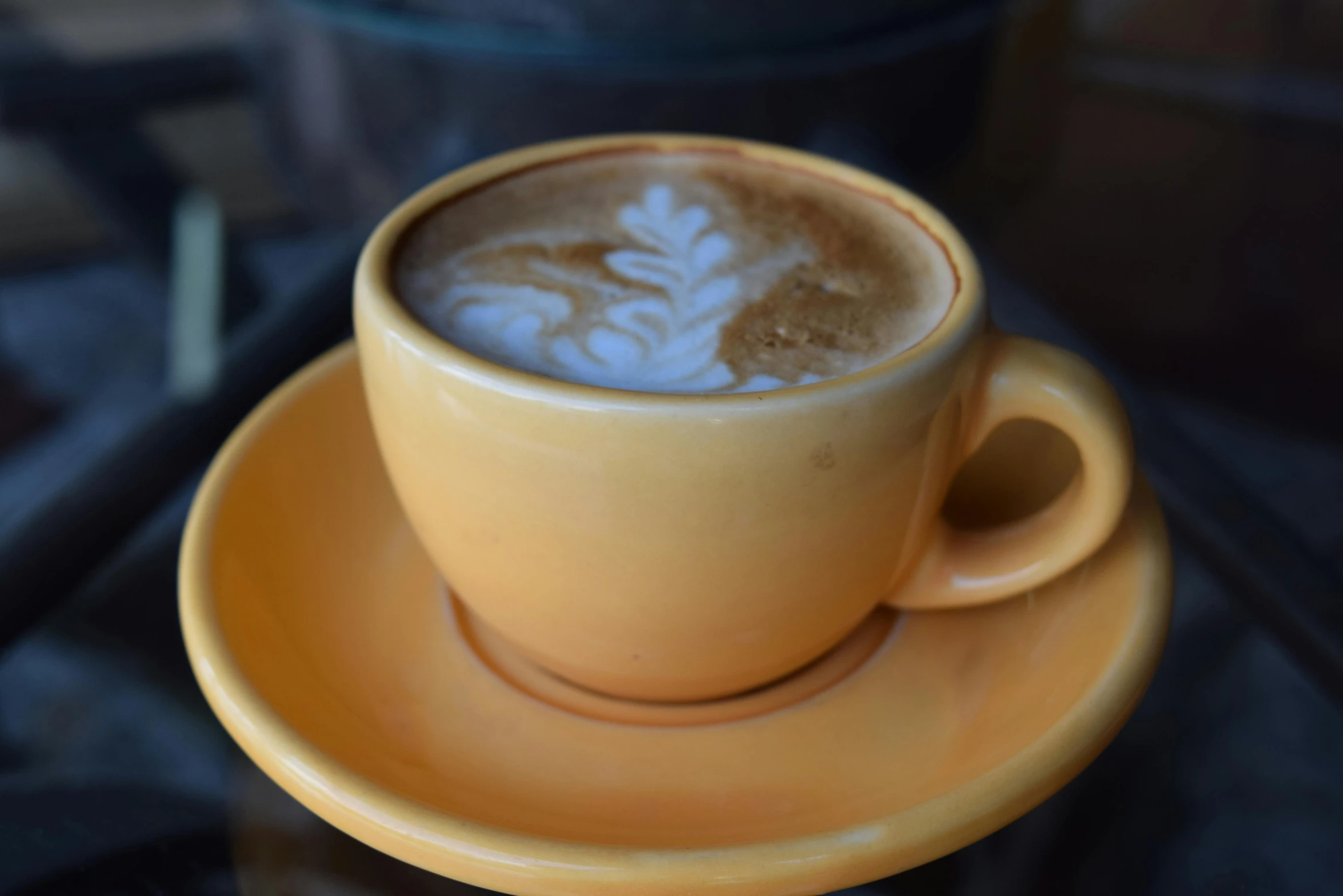 a cup of coffee sitting on top of a saucer, by Jessie Algie, pexels, yellow, california;, cappuccino, unedited