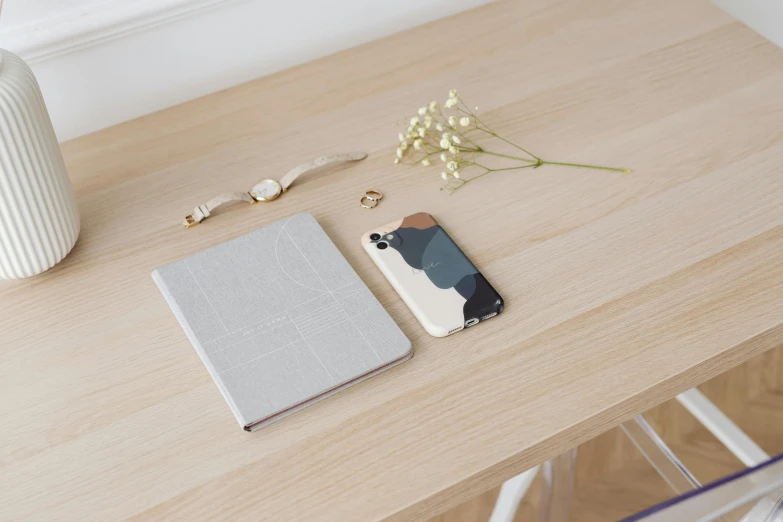 a white vase sitting on top of a wooden table, a picture, inspired by Jean Arp, minimalism, silicone cover, iphone 1 3 pro max, grey and silver, pair of keycards on table