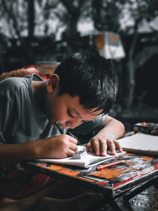 a boy sitting at a table writing on a piece of paper, by Byron Galvez, pexels contest winner, process art, asian male, 15081959 21121991 01012000 4k, working hard, absolutely outstanding