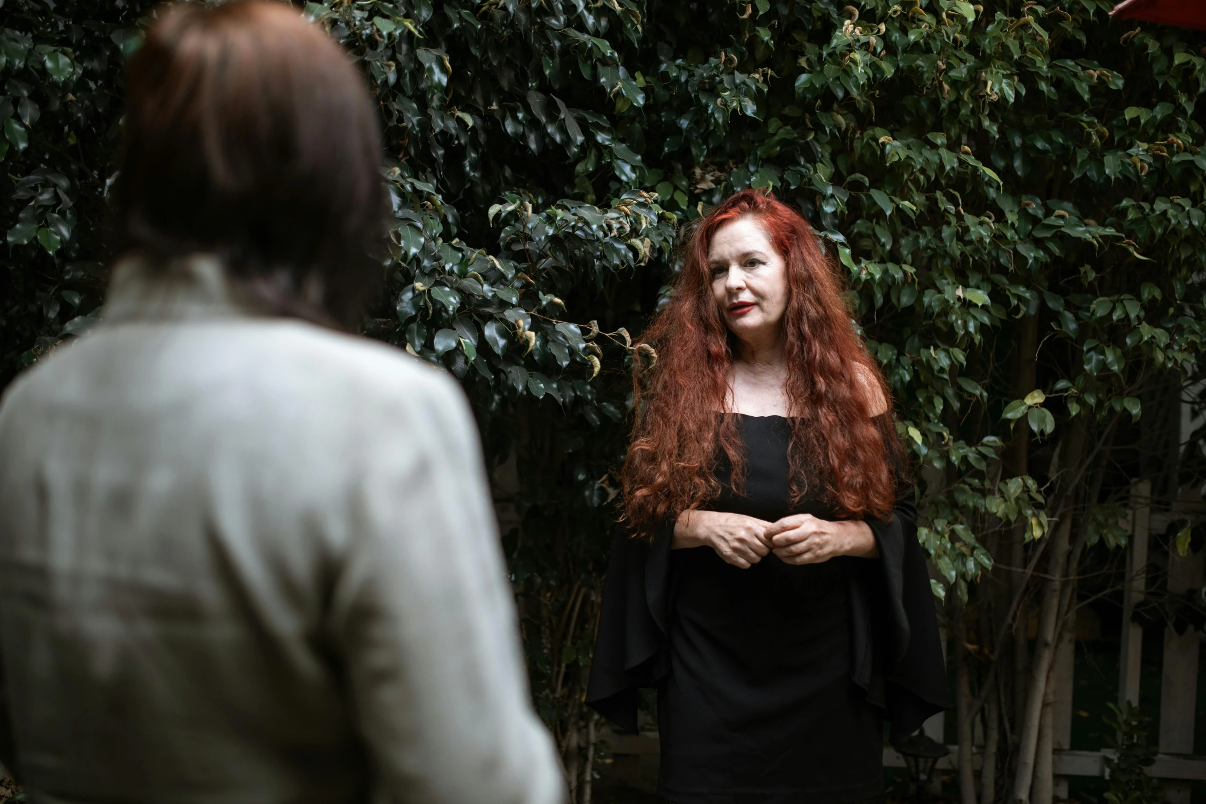 a woman with long red hair standing next to a man, by Lisa Milroy, pexels contest winner, a seance, in garden, facing to audience, in style of nan goldin