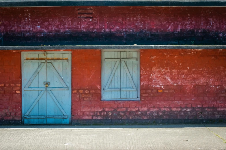 a red brick building with two blue doors, by Peter Churcher, unsplash, bengal school of art, shack close up, 3 colours, barn, multicolored