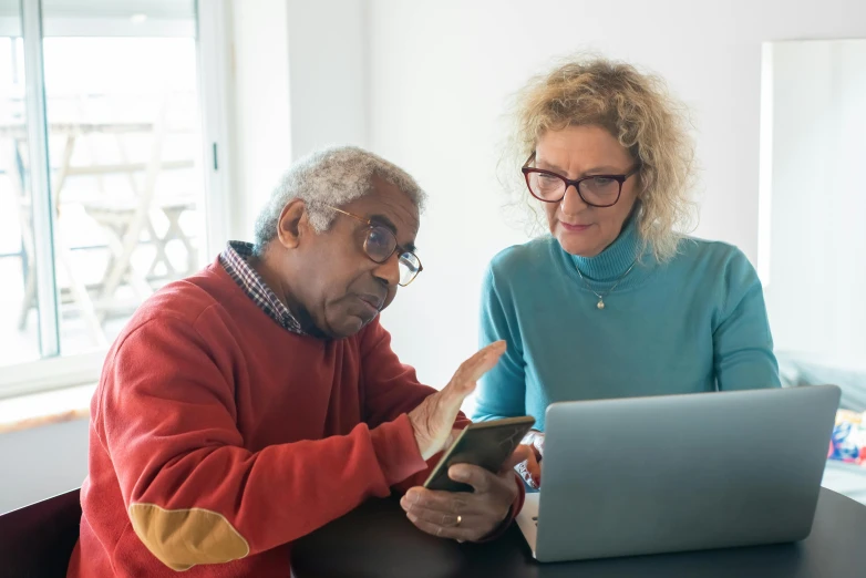 a man and woman sitting at a table looking at a laptop, dementia, digital still, diverse, gorecore