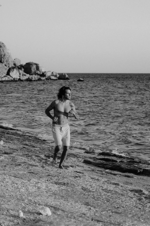 a black and white photo of a man running on the beach, by Alexis Grimou, frank dillane as a satyr, white beaches, young greek man, single